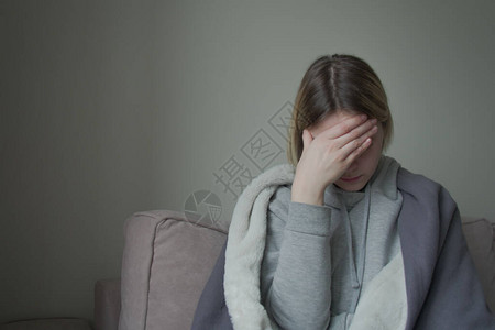 心烦意乱的抑郁年轻女坐在沙发上感觉强烈的头痛偏头痛图片