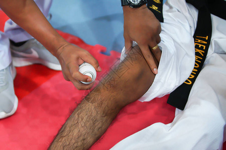 EMS护士在受伤运动员的腿上施了热冷却喷雾图片