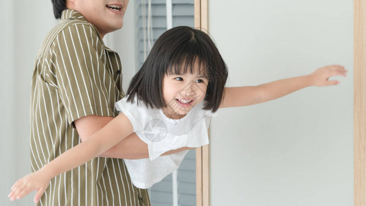 一个有着可爱父亲和女儿的亚洲家庭他们在卧室里玩得很开心父亲抱起女儿图片
