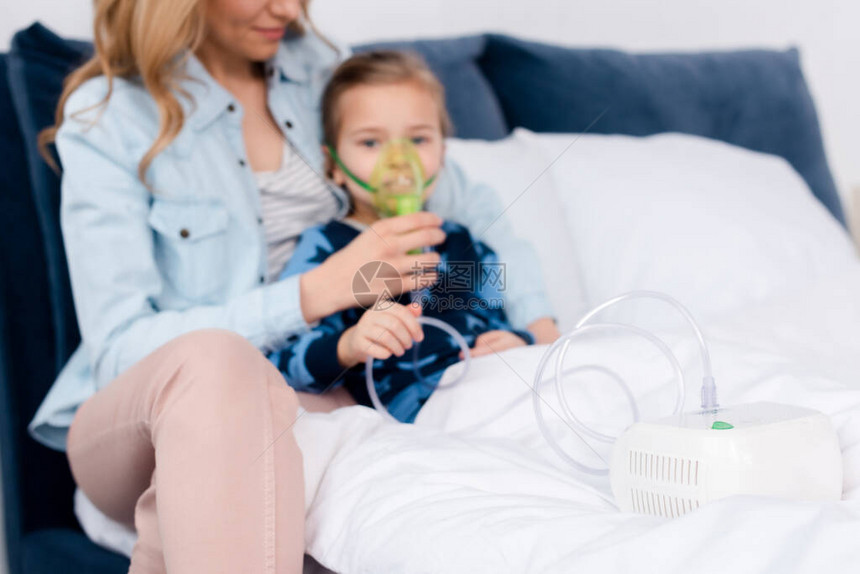 在哮喘病孩子和有照护的母亲附近使用压缩机吸入器图片