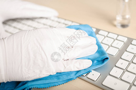 戴着手套的手用消毒剂清洁键盘COVID19冠状爆发图片