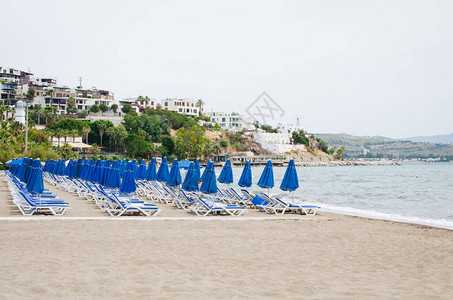 沙滩上有一排空的蓝太阳护林员和雨伞背景图片