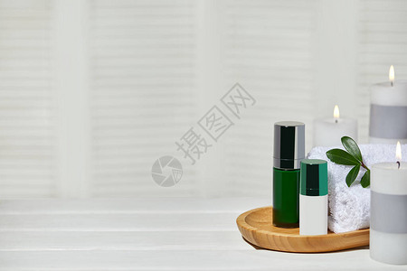 白色木制桌子上的天然化妆品芳香蜡烛和毛巾图片