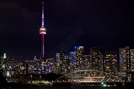 在多伦市中心摩天大楼的夜景与明亮的窗户与色彩缤纷的加拿大电视塔图片