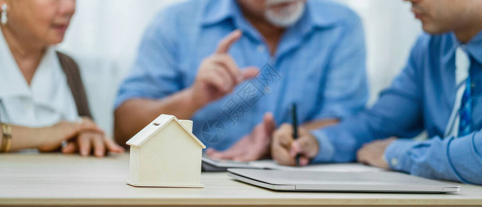 保险代理经与亚洲夫妇祖父母在交易成功后与笔记本电脑签订横幅房屋模型图片