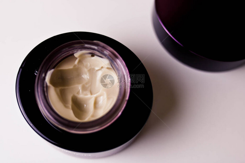 彩色化妆品奶油在紫玻璃锅上转动图片