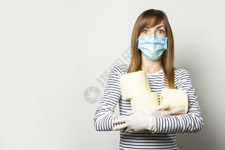 身戴医疗面具和手套的惊恐少女携带着一副轻薄背景的卫生纸卷图片