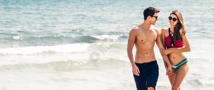 度假浪漫情侣手牵在海边沙滩上散步图片