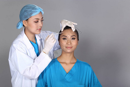 亚洲医生护士在整形手术前检查面部前额结构图片