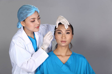 亚洲医生护士在整形手术前检查面部前额结构图片
