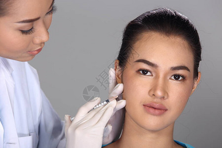 亚洲医生护士在整形手术前检查脸颊结构并向患者注射美容化学注射器图片