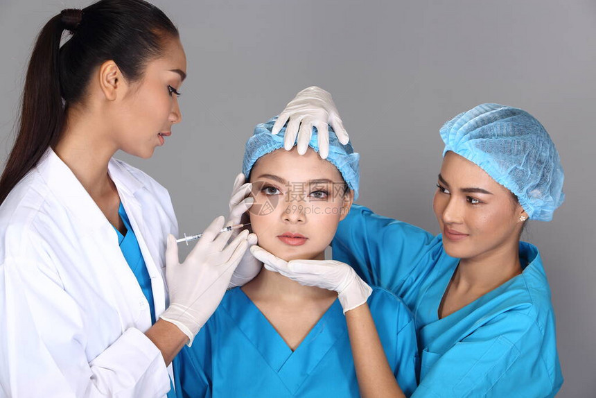 亚洲医生护士组在整形手术前检查脸颊骨结构并向患者注射美容化学注射器图片