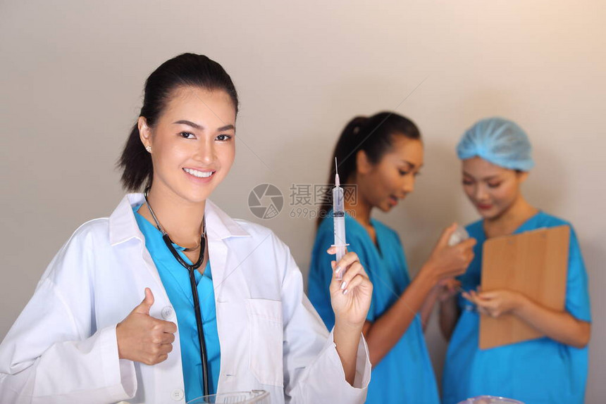 穿白衬衫听诊器的亚洲美丽的女医生展示了针筒拇指图片
