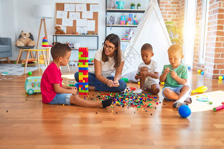 年轻漂亮的老师和幼儿在幼儿园的许多玩图片