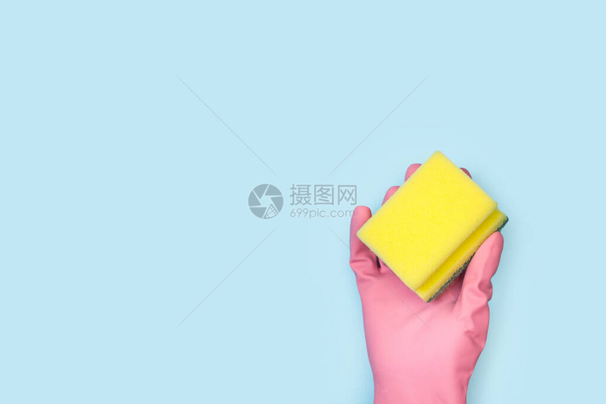 用粉色橡皮手套握着清洁海绵的手图片