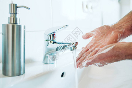 用肥皂和热水在浴室水槽彻底洗手的人特写图片