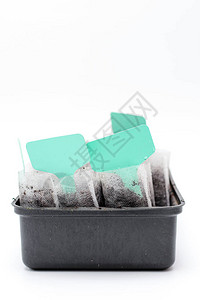 白色编织的物袋与土壤在一个黑色塑料容器反对白色背景图片
