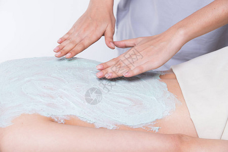 在健康水疗中心的亚洲女皮肤上涂淡绿色草药美容护理背景图片