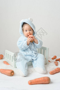 一个穿着装的小女孩正在吃胡萝卜健康的生活方式概念孩子图片