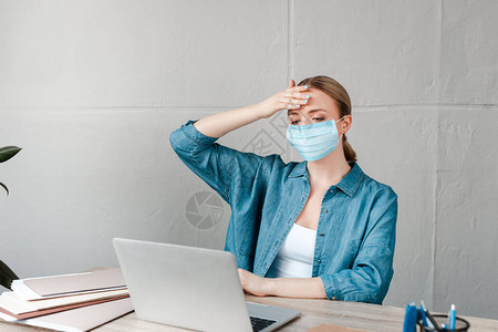 妇女在办公室用笔记本电脑工作时戴医疗面罩图片