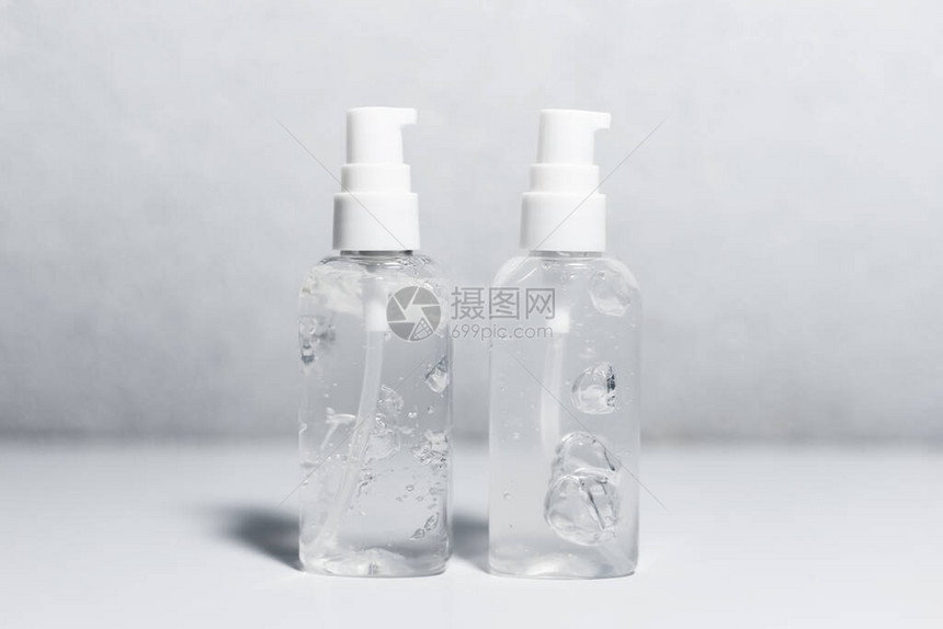 白色桌子上两瓶装有消毒剂抗菌凝胶的便携式塑料瓶关闭图片