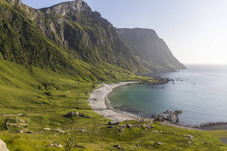 令人惊叹的挪威海滩水晶般清澈的海洋白色沙滩绿色山脉和悬崖的顶部景色背景图片