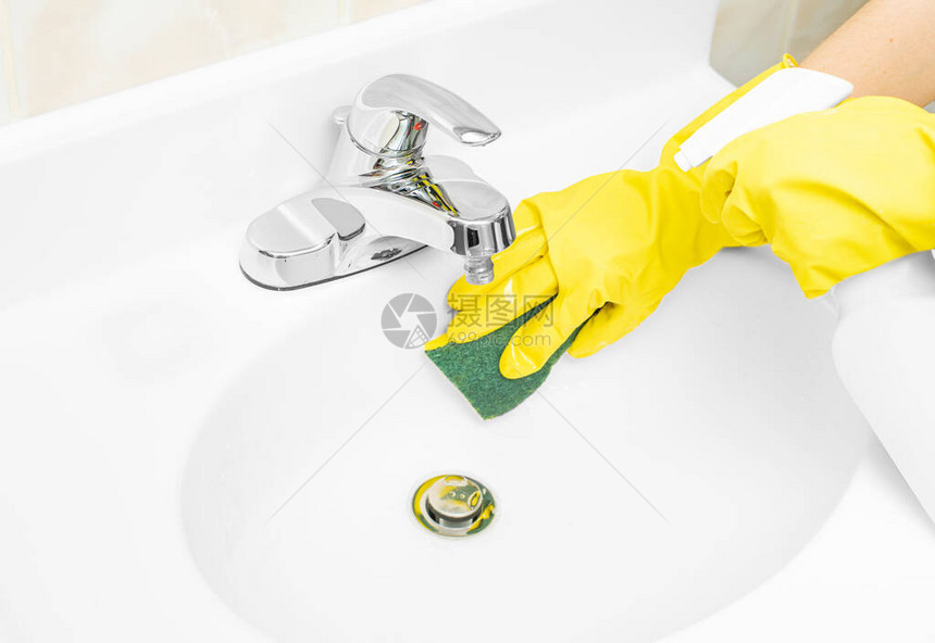 戴黄色橡胶手套的妇女正在用洗涤剂和海绵图片