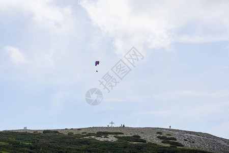 在山上漂浮的滑翔伞和徒步旅行者图片