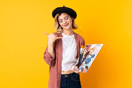 年轻艺术家女孩拿着一个调色板孤立在黄色背景的黄色背景图片
