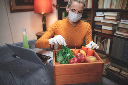 戴着医用防护面罩的妇女在网上订购的食物背景图片