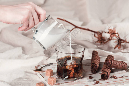 奶油泡在一杯冰咖啡里女人的手握着一罐牛奶甜早餐加冷饮复制文图片