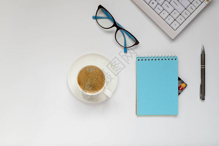 一个键盘一杯咖啡一支笔眼镜和一个笔记本图片