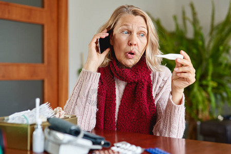 生病的成年妇女坐在家里打电话感知到发烧流感或图片