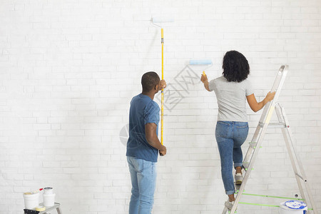 非洲裔美国夫妇用滚筒刷墙图片