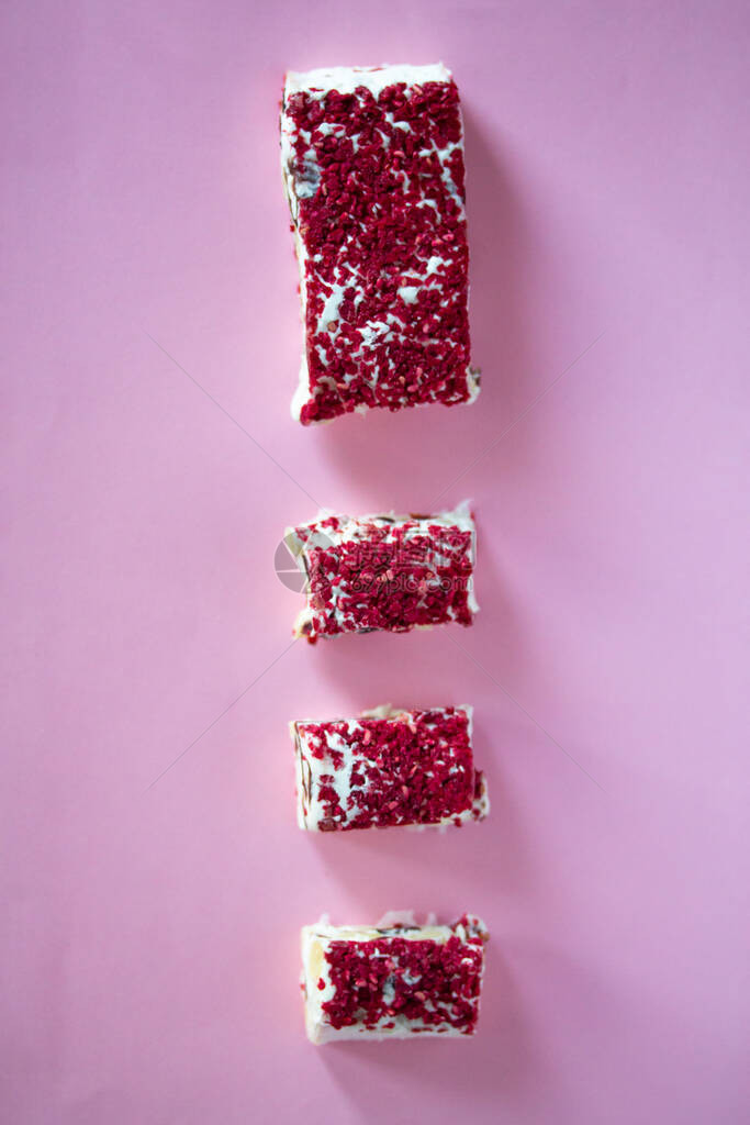 Torrone或牛轧糖棒与坚果和红色干浆果传统的意大利甜点靠近粉红色的背景甜可口图片