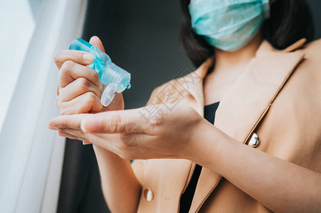 戴面罩保护亚洲妇女免受冠状感染的亚裔妇女使用酒精凝胶图片