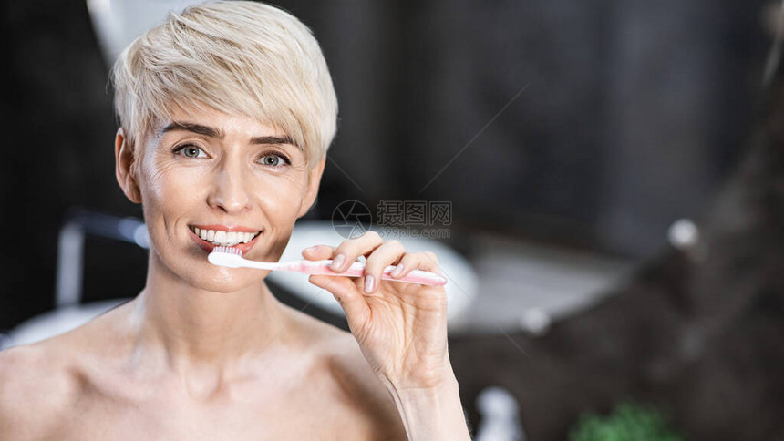 妇女用牙刷打扫牙齿图片