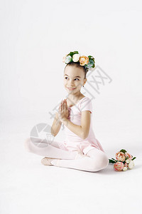 可爱的女孩芭蕾舞女郎坐在白色背景上图片