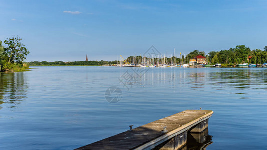 机动船和帆船停泊在湖泻码头或停靠在绿河芦苇和尝试的码头上图片