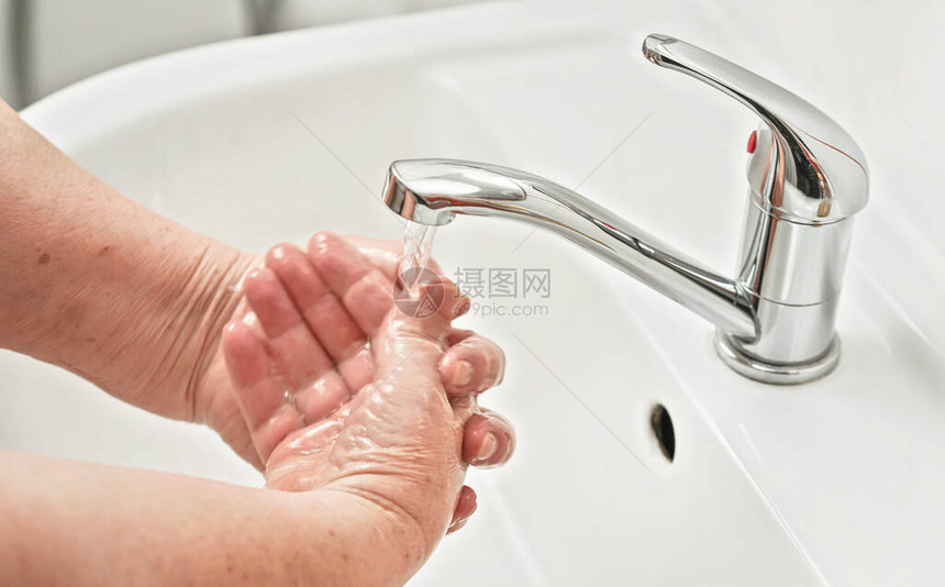 老年妇女在自来水龙头下洗手图片
