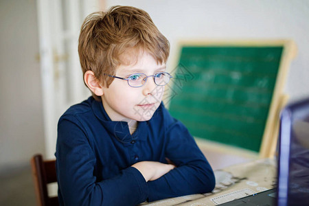 开局之年戴着眼镜在电脑上做学校作业的小学生儿童在pc上学习的男孩在隔离期间因电晕流行病而锻炼在背景
