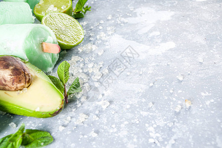 自制鳄梨冰棒素食非乳制品冰淇淋灰石背景中的鳄梨石灰和椰子健康冰棒图片