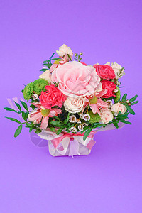 在紫色背景上用粉红色包装的花束包着一束花图片