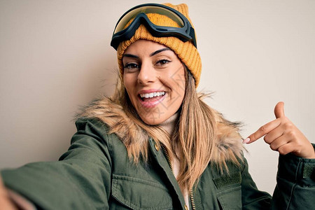 穿着雪衣和滑雪护目镜的黑发滑雪年轻女子用相机自拍图片