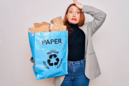 年轻漂亮的红发女人回收拿着纸袋和纸板来回收图片