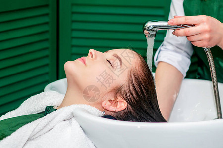 美发师在美容院的水槽里给女人洗头发图片