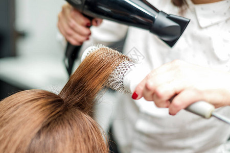 专业美发师用吹风机吹干头发吹风机概念理发沙龙图片