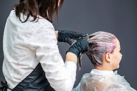 美发师在美容院为年轻女子的头发上色图片