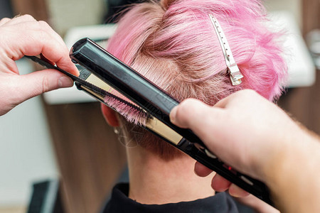 专业美发师在美容院概念理发店女造型师用直发器图片