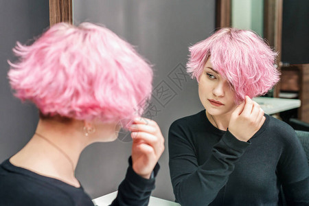 有粉色头发的女孩照着镜子看她的新发图片